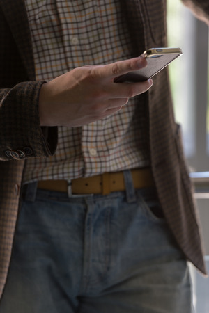 Unrecognizable stylish businessman texting on the phone in officeの写真素材