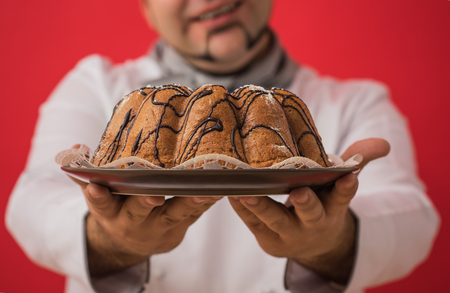 Portrait of caucasian man with chef uniform sharing fresh cakeの写真素材