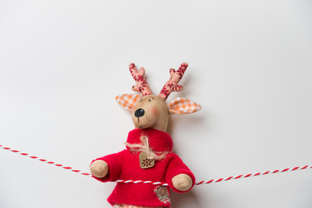 Handmade vintage Christmas deer hanging on a ribbon on white background with copyspaceの写真素材