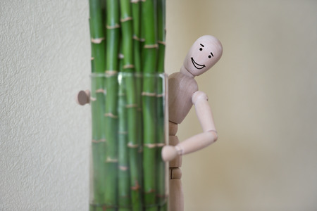 Wooden man standing at home and looking out of the tree. People emotions concept. Drawn facesの写真素材