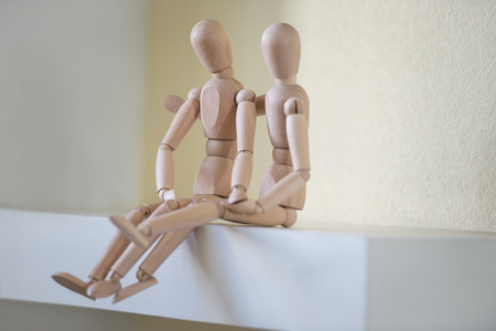 Wooden people sitting at home and hugging. People relationship conceptの写真素材