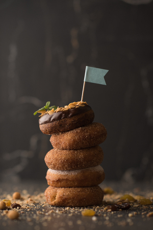 Stack of Donuts with crumbs, nuts and flag on dark stone backgroundの写真素材