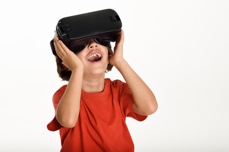 Little girl looking in VR glasses and gesturing with his hands. Cheerful surprised child wearing...