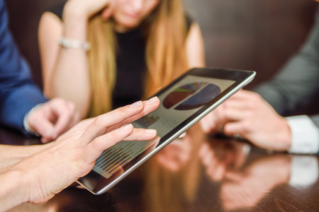 Close-up of a modern business team using tablet computer to work with financial data 