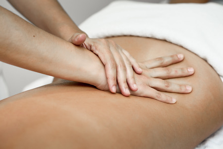 Young woman receiving a back massage in a spa center. Female patient is receiving treatment by professional therapist.の写真素材