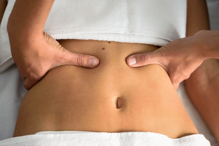 Hands massaging female abdomen.Therapist applying pressure on belly. Woman receiving massage at spa...