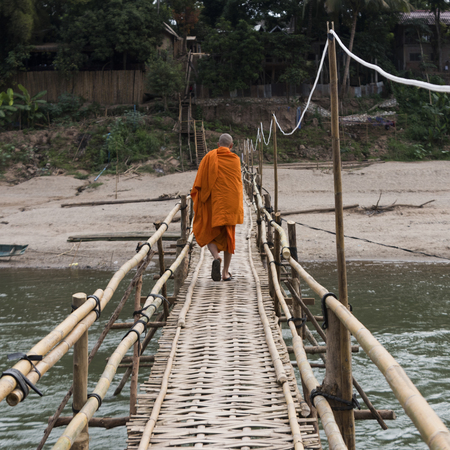 Monk walking on bamboo bridge over Nam Khan river, Luang Prabang, Laosの写真素材
