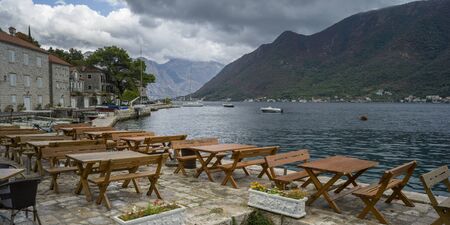 Empty tables and chairs at waterfront restaurant, Perast, Bay of Kotor, Montenegroの写真素材