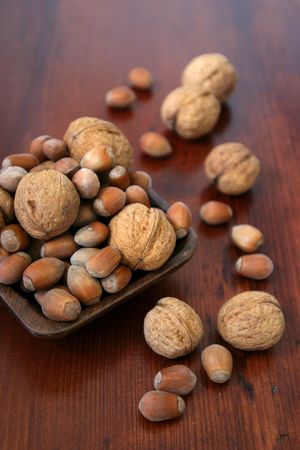 Wooden bowl with hazelnuts and walnuts on a wooden tableの写真素材