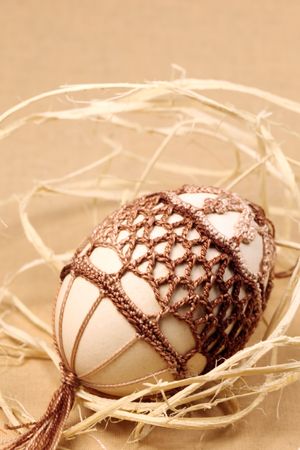 Easter egg with brown crochet decoration. Shallow DOF, copy spaceの写真素材