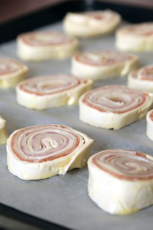Raw puff pastry rolls with ham, salami and cheeseの写真素材