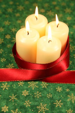 Four candles with red ribbon on green Christmas background. Shallow DOF, copy space.の写真素材