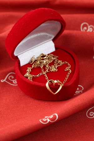 Golden necklace with heart in a heart shaped boxの写真素材