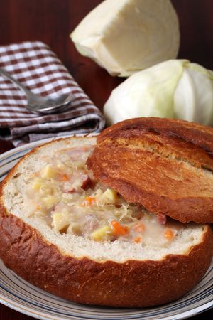 Traditional Czech cabbage soup made from sauerkraut with potato, carrot and meat sausage, served in a bread bowlの写真素材