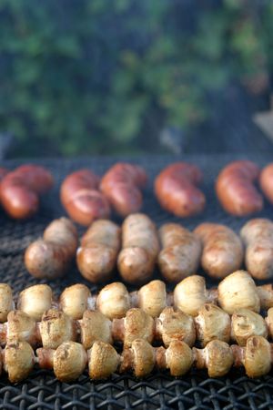 Mushrooms and different kinds of sausages on grillの写真素材