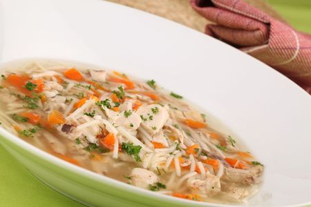 Chicken soup with pieces of meat, carrot, noodles and parsleyの写真素材