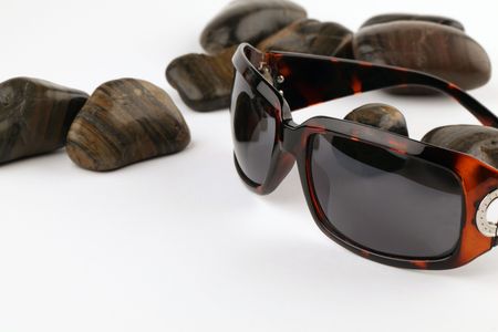 Stylish sunglasses and black pebbles on white backgroundの写真素材
