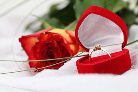 Golden engagement ring in a heart shaped box and rose. White background, shallow DOFの写真素材