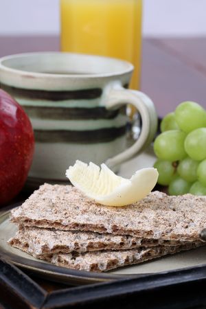 Healthy breakfast consisting of fresh fruits, crackers with butter, orange juice and tea or coffeeの写真素材