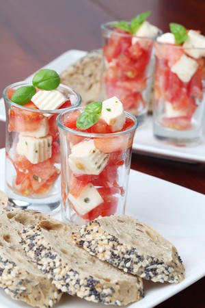 Caprese appetizers with tomatoes, mozzarella and basil in small glassesの写真素材