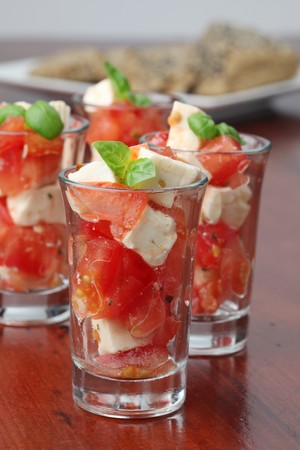 Caprese appetizers with tomatoes, mozzarella and basil in small glassesの写真素材