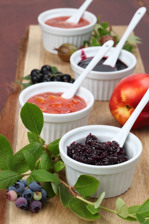 Blueberry, nectarine, black currant and gooseberry jams on a wooden boardの写真素材
