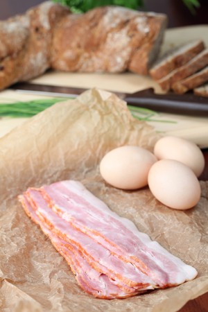 Bacon and eggs on waxed paper with chives and bread in the background. Ingredients for delicious breakfast. の写真素材