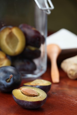 Preserving plums: jar with plums, sugar and ginger on a tableの写真素材