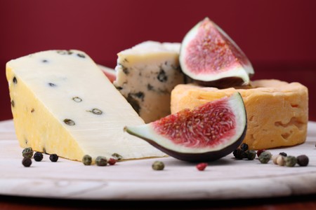 Various kinds of cheese with fresh figs on a cutting boardの写真素材