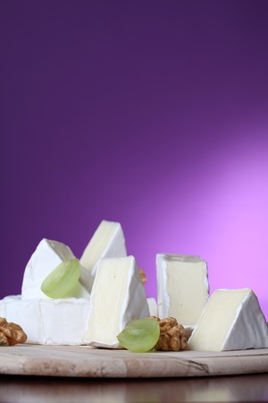 Camembert cheese on cutting board with walnuts and grapesの写真素材