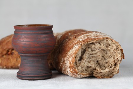 Chalice with red wine and bread in background. Shallow dof, copy spaceの写真素材