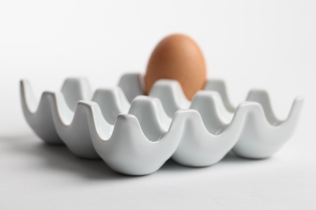 Ceramic egg holder with one brown chicken egg. Shallow dofの写真素材