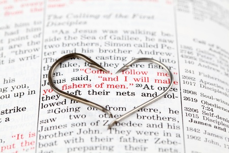 Fishing hook on the Bible with focus on Matthew 4:19 where Jesus calls disciples to be fishers of menの写真素材