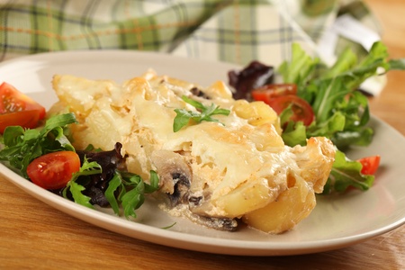 Potato gratin with mushrooms, eggs, cheese and mixed greensの写真素材