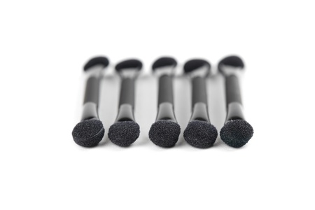 Close-up of five black make-up applicators isolated on white background