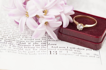 Gold engagement ring with diamond on the Bible open to 1st Corinthians 13, a passage about love  Shallow dofの写真素材