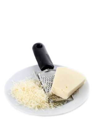 Grated cheese and grater on a plate isolated on white backgroundの写真素材