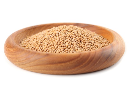 Mustard seeds in a wooden bowl isolated on white backgroundの写真素材