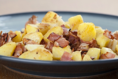 Roasted potatoes with crispy bacon on a plateの写真素材