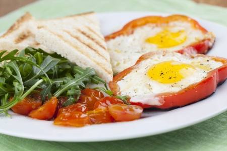 Eggs fired in bell pepper frames with cherry tomatoes and arugulaの写真素材