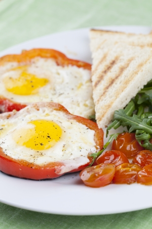 Eggs fired in bell pepper frames with cherry tomatoes and arugulaの写真素材