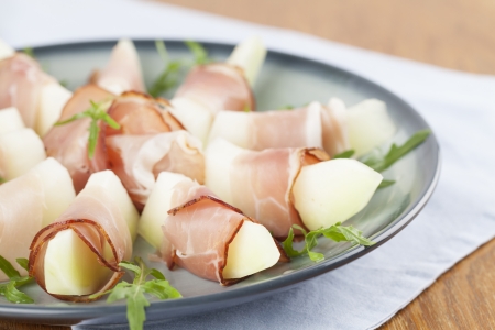 Prosciutto and honeydew melon appetizers with arugulaの写真素材
