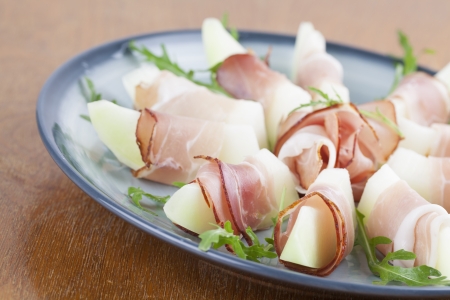 Prosciutto and honeydew melon appetizers with arugulaの写真素材