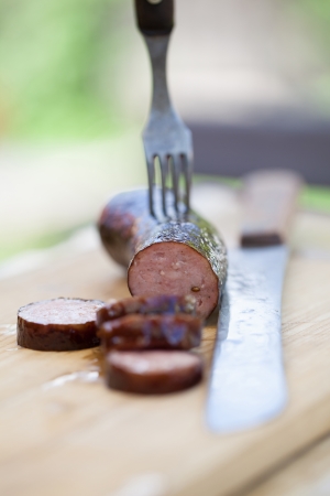 Right from a smokehouse, still warm and juicy sausage on a cutting boardの写真素材