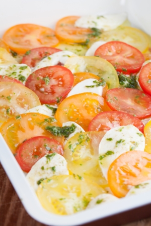 Colorful tomatoes with mozzarella and pesto on baking sheetの写真素材