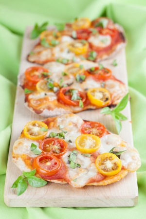 Mini pizzas with mozzarella, colorful cherry tomatoes and basilの写真素材