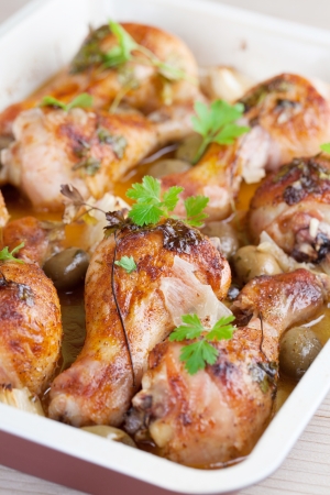 Roast chicken drumsticks with green olives and onion on a baking sheetの写真素材