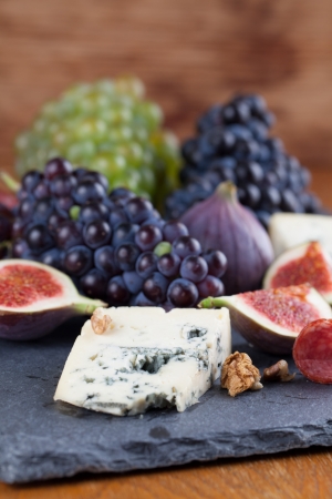 Slate board with blue cheese, blue and green grapes, figs, walnuts and salamiの写真素材