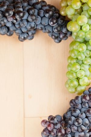 Blue and green grapes frame on wooden backgroundの写真素材
