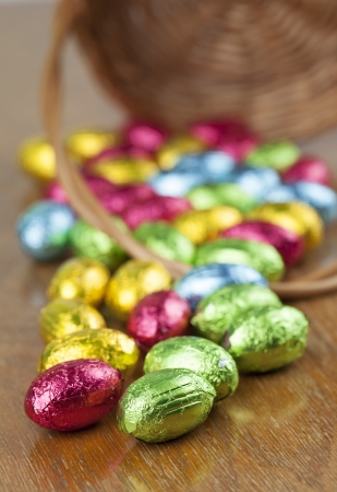 Colorful chocolate Easter eggs on the table and basket の写真素材